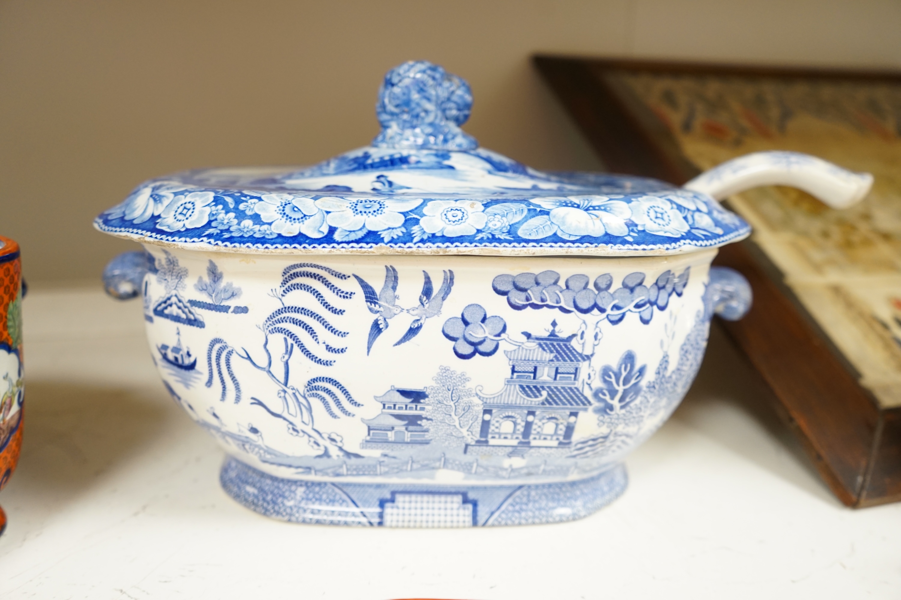 A large early to mid 19th century Pearlware meat platter and tureen without cover decorated with the ‘doctor calling’ pattern with a blue and white tureen cover and ladle, meat platter 54cm wide (3). Condition - fair